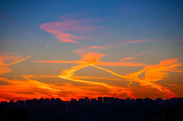Orange clouds with aircraft trails sky background and city light midnight evening time — Stock Photo, Image