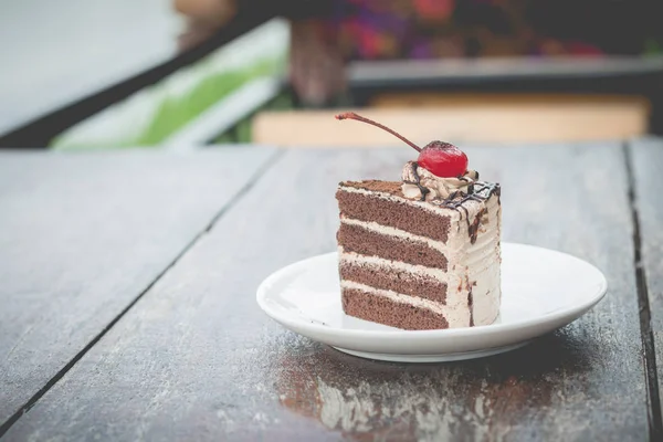 chocolate cake with cherry topping in cozy outdoor cafe