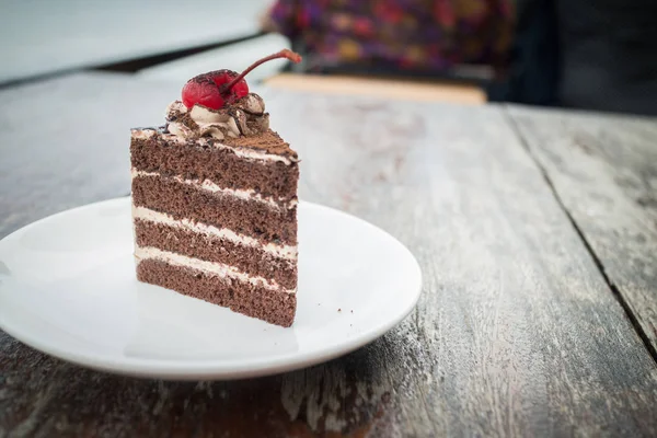 chocolate cake with cherry topping in cozy outdoor cafe