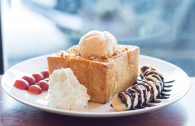 Vanilyalı dondurma, krem şanti ve çikolata şurubu ile bal tost. Muz, üzüm ve elma ile servis edilir (seçici odak)