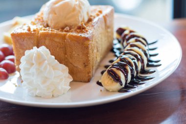 Vanilyalı dondurma, krem şanti ve çikolata şurubu ile bal tost. Muz, üzüm ve elma ile servis edilir (seçici odak)