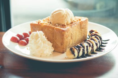 Vanilyalı dondurma, krem şanti ve çikolata şurubu ile bal tost. Muz, üzüm ve elma ile servis edilir (seçici odak)