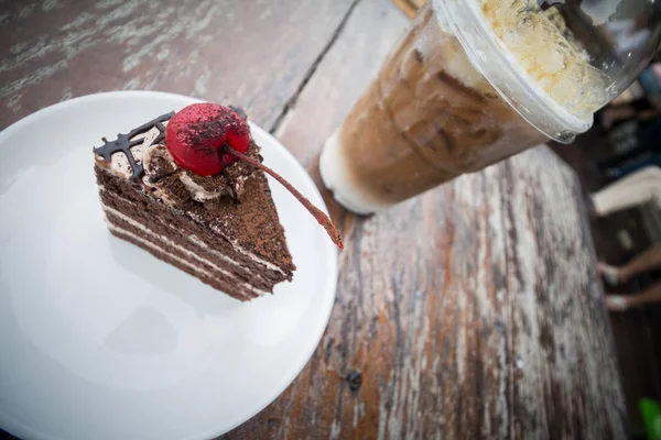 chocolate cake with cherry topping and ice coffee mocha in outdoor cafe