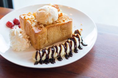 Vanilyalı dondurma, krem şanti ve çikolata şurubu ile bal tost. Muz, üzüm ve elma ile servis edilir (seçici odak)