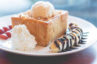 Vanilyalı dondurma, krem şanti ve çikolata şurubu ile bal tost. Muz, üzüm ve elma ile servis edilir (seçici odak)