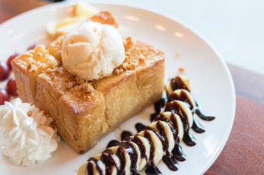 Vanilyalı dondurma, krem şanti ve çikolata şurubu ile bal tost. Muz, üzüm ve elma ile servis edilir (seçici odak)