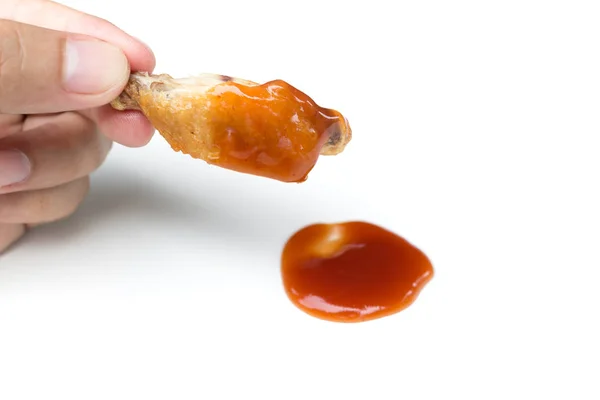 Ręka trzymanie smażone skrzydła kurczaka i ketchup izolowane na białym b — Zdjęcie stockowe