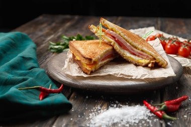 Panini yığını bir kesme tahtası üzerinde jambon, peynir ve salata sandviç ile