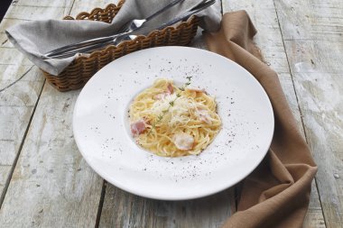 Makarna Carbonara. Pastırma ve parmesan peynirli spagetti. Beyaz tabakta makarna Carbonara koyu arka plan üzerine parmesan ile