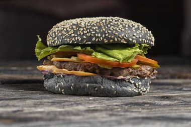 Siyah hamburger ızgara soğan, domates dilimleri ve marul dolması kapat