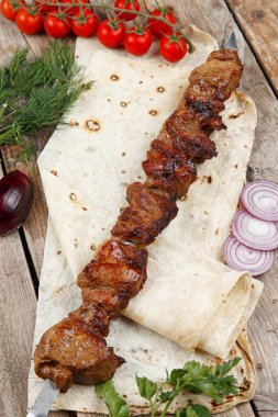 ahşap bir masada çeşitli barbekü şişler