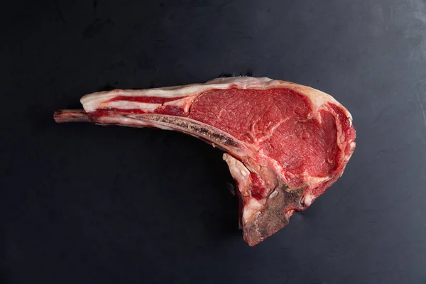 Steak d'os cru classique sur fond noir. Gros plan — Photo