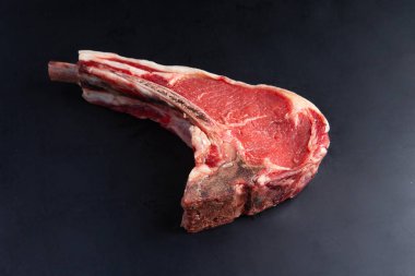 Siyah arka planda klasik çiğ kemik bifteği. Yakın plan.
