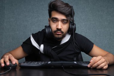 Genç oyuncu gri bir arka planda bilgisayarın başında uyuyakalıyor.