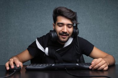 Genç oyuncu gri bir arka planda bilgisayarın başında uyuyakalıyor.