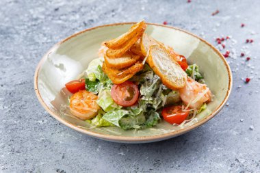 Gri arka planda karides ve kızarmış ekmek tabağında salata.
