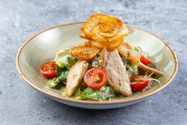 Insalata con pollo e crostini in un piatto su sfondo grigio — Foto Stock