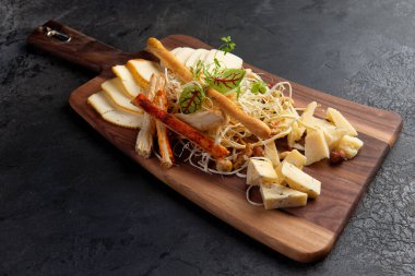 Çeşitli peynirli, fındıklı peynir tabağı, ahşap bir arka planda ekmek. Koyu bir tahta üzerinde..