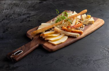 Çeşitli peynirli, fındıklı peynir tabağı, ahşap bir arka planda ekmek. Koyu bir tahta üzerinde..