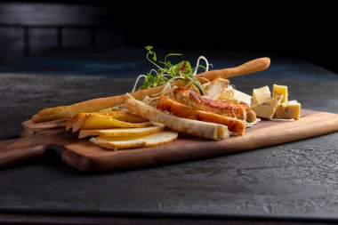 Çeşitli peynirli, fındıklı peynir tabağı, ahşap bir arka planda ekmek. Koyu bir tahta üzerinde..