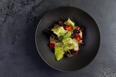 Domatesli salata ve siyah tabakta otlar. Seçici odak