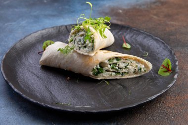 Piita, siyah bir tabakta peynir ve otlarla yuvarlanıyor. seçici odak