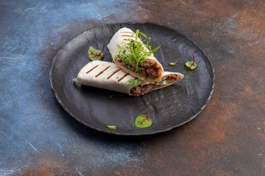 Piita siyah bir tabakta et ve otlarla yuvarlanıyor. seçici odak