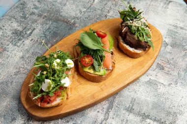 Sığır eti, somon, domates, biber ve roka ile servis edilmiş bruschetta.