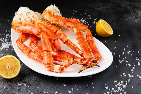 Crab legs in a plate on a dark background. Ready to eat. — Stock Photo, Image