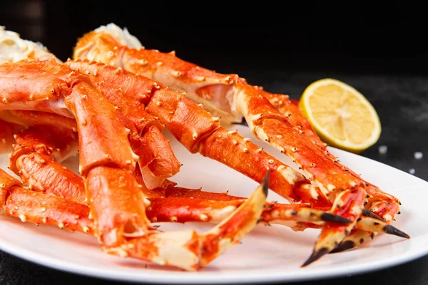 Crab legs in a plate on a dark background. Ready to eat. — Stock Photo, Image