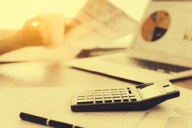 Bir dizüstü bilgisayar ve kahve içme ve sabah ışık gazete okuyan bir işadamı bir arka plan ile masa üzerinde hesap makinesi. sıcak sesi.