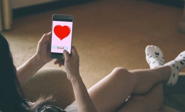 Sevgililer günü kavramı. Adama kırmızı kalp resim göndermeye mobil akıllı telefonlar kullanan kadın seviyor.