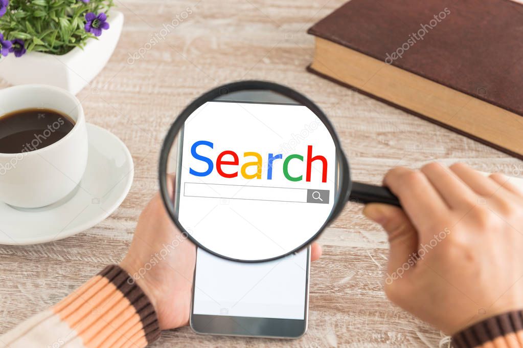 Search and modern lifestyle concept. Women hands Use the magnifying glass screen smart phone for search data on the desk.