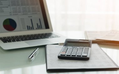 Finansal muhasebe konsepti. Ekonomi grafiği ve masadaki ekran dizüstü bilgisayarı ile iş kazanç raporu hesaplayıcı.
