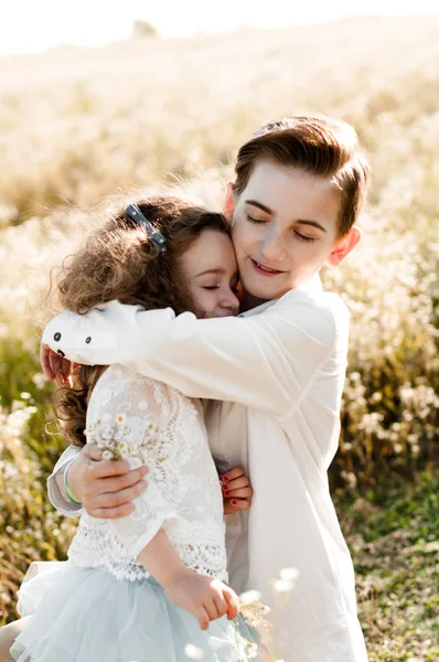 Oudere Broer Knuffels Zijn Kleine Zusje Een Veld Van Daisy — Stockfoto