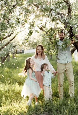 çiçek açan elma meyve bahçesinde oynayan iki çocuklu genç güzel aile