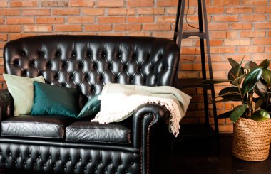 Tuğla duvar karşısında siyah deri kanepe ile Loft iç