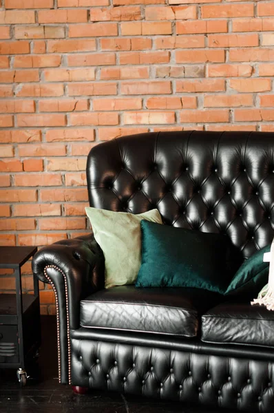 レンガの壁の向かいに黒い革のソファが付いているロフトの内部 — ストック写真