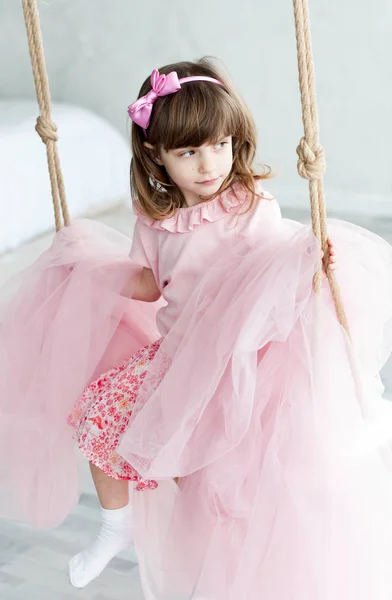 Милая Маленькая Девочка Розовой Одежде Луком Волосах Качелях Помещении — стоковое фото