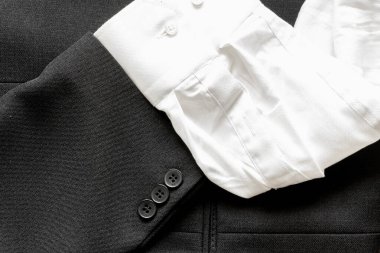 İş elbisesi ve beyaz gömlek kolundaki birkaç düğmeyi kapat.