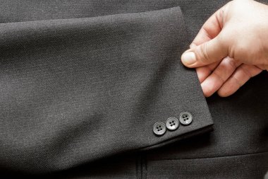İş elbisesinin kolunda birkaç düğme olan bir kol.