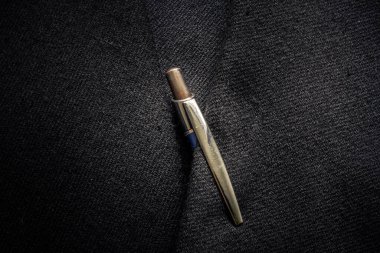 İş ceketinde metalik mavi bir kalemle takım elbise dokusunun yakın çekimi.