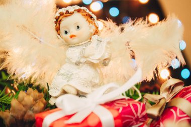 Noel arkaplanı, çam ağacı dalları, hediyeler ve mavi ve sarı ışıklı küçük bir melek bebeği. Renkli mücevherler, mavi tatil süslemeleri.