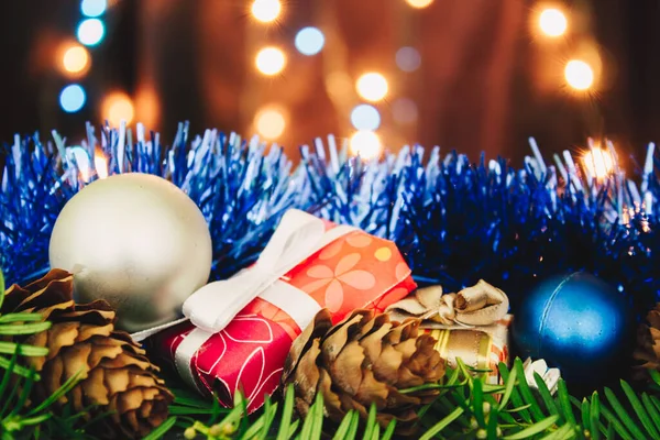 Karácsonyi Háttér Fenyőágakkal Ajándékokkal Fenyőtobozokkal Kék Sárga Fényekkel Színes Baubles — Stock Fotó