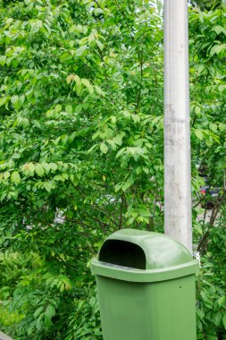 Ekoloji kavramı. Arka planda ağaçlar olan bir sütuna asılmış çöp kutusu.