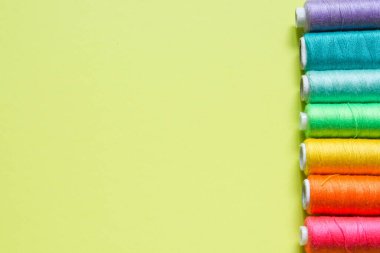 Limon yeşili arka planda dikmek için ruloların üzerine renkli pamuk iplikleri