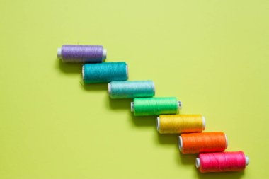 Limon yeşili arka planda dikmek için ruloların üzerine renkli pamuk iplikleri