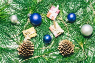 Yılbaşı baloları, hediyeler, kozalaklar ve yeşil çam yapraklarıyla Noel arkaplanı..