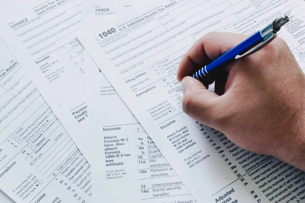 US tax form 1040 with hand holding a pen. tax forms law documents. USA business mathematics concept