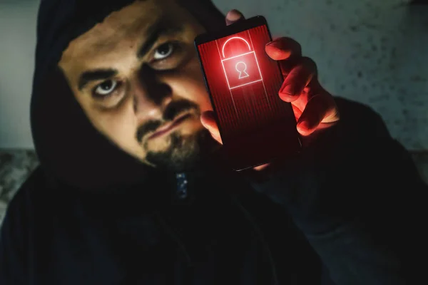 Elinde siyah ekranlı bir telefon tutan öfkeli bir hacker. Siber saldırı uyarısı. Fidye yazılımı kavramı